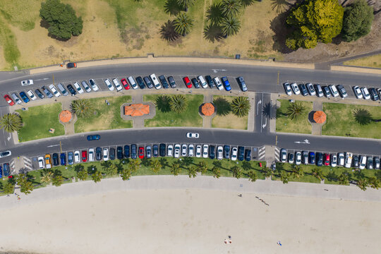 Rows of cars parked beside the road through a waterfront reserve