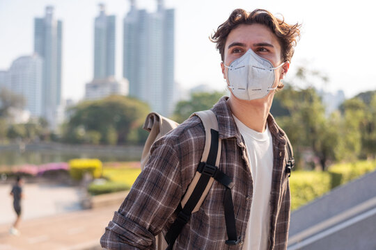 Man wearing face mask and backpack in park during warm weather