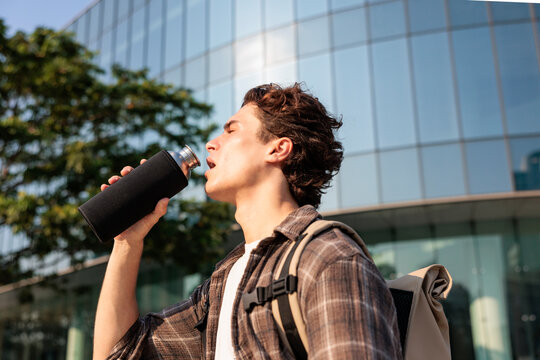 Man quenching thirst in urban heat with water bottle