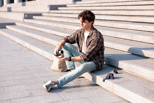 Man sitting on urban steps pouring water in hot weather