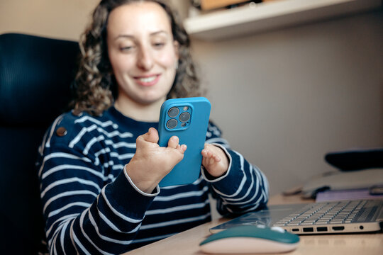 Young woman with disability using smartphone at office desk