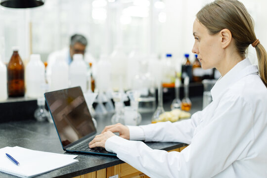 Tired woman scientist working on computer in real laboratory.