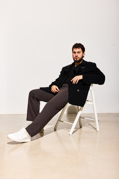 Man sitting on a chair in a simple studio setting