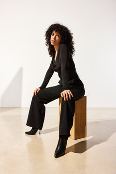 Woman sitting on a wooden stool in a studio setting
