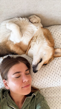 Woman and corgi dog sleeping together on bed
