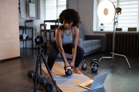 Black sportswoman lifting kettlebell near camera