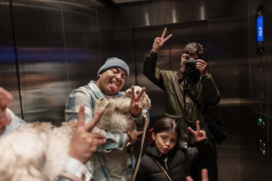 Family making peace signs and taking selfie in elevator