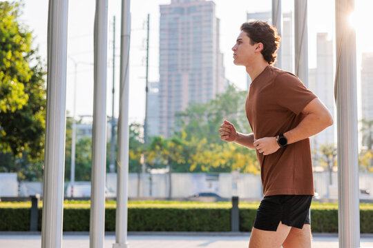 Man jogging in city park with skyscrapers in background.
