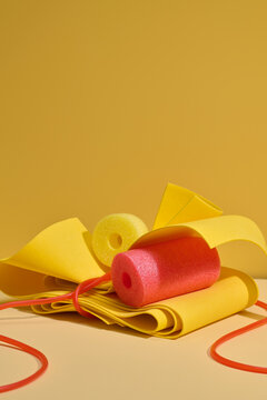 Bright yellow and red foam objects arranged with elastic bands
