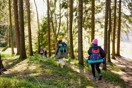 Family hiking through forest trail with backpacks