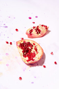 Pomegranate on paint splattered surface with flowers 
