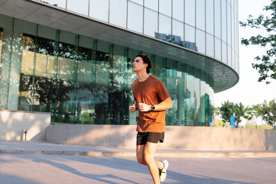 Man jogging in urban heat near modern glass building