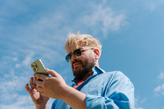 Man looking at phone under cloudy sky