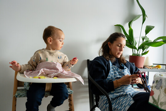 Mother using phone while baby eats