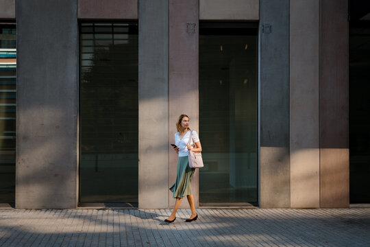 A woman uses a smartphone while walking in the city