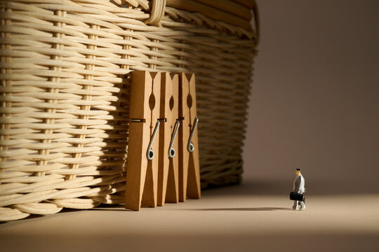 Miniature businessman walks towards a large woven basket