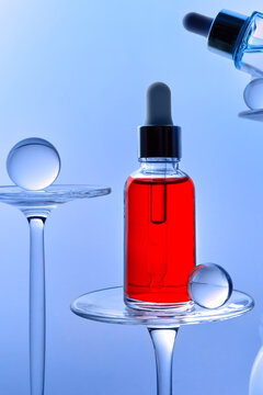 Red serum in glass dropper bottle on teal blue background