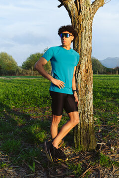 Young man leaning against tree in outdoor setting