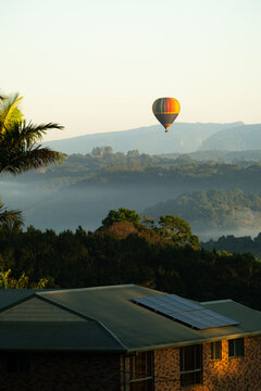 Hot air balloon floating above misty hills at sunrise