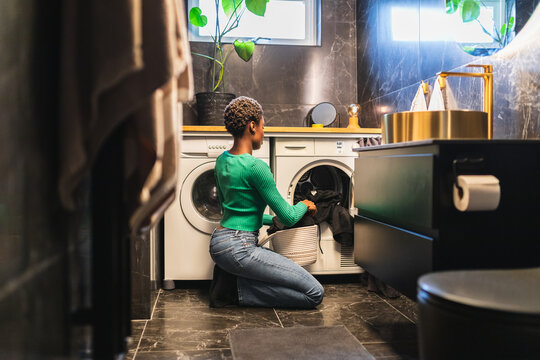 Woman Loading Washing Machine in Modern Compact Basement Bathroom