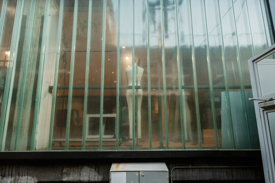 Mannequin standing inside a shop window with reflections