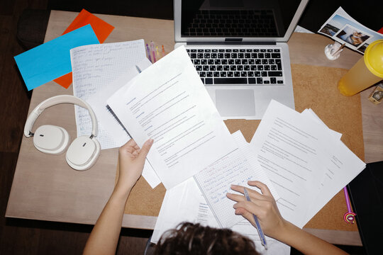 Person studying with laptop and papers on desk