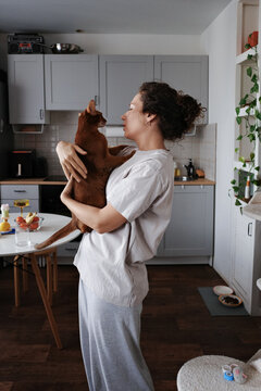 Person holding cat, showing affection in kitchen