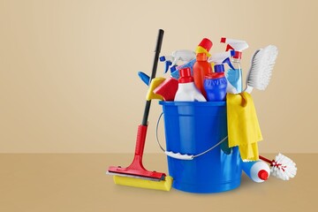 Household cleaning supplies and tools sitting in a blue bucket against a beige background © BillionPhotos.com