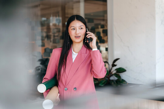 Young Architect Holding Plans and Phone in Modern Office