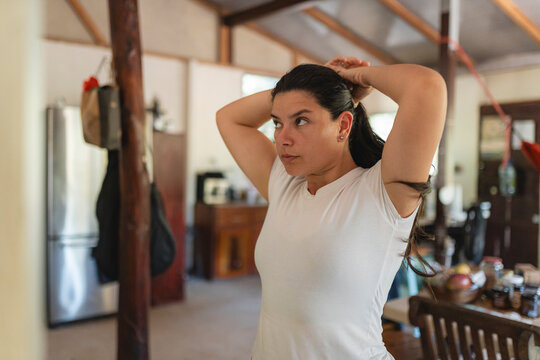 Woman tying dark hair in casual home setting