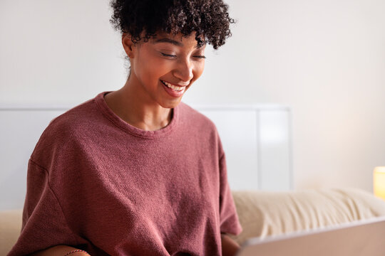 Smiling woman using laptop in bed.