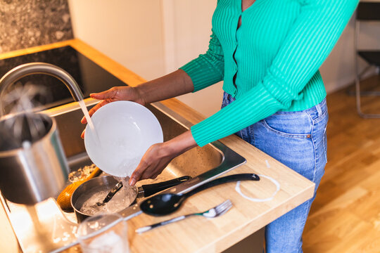 Close-up of Woman Washing Dishes in Compact Modern Kitchen