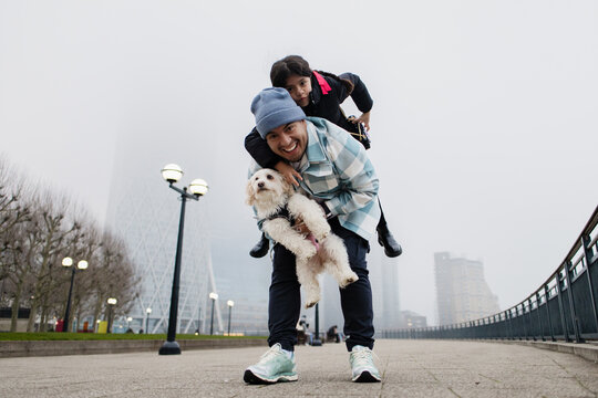Happy family having fun piggybacking with pet dog