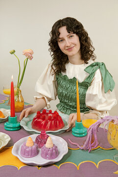 Woman sitting at the colorful festive table with jelly sweets, dessert