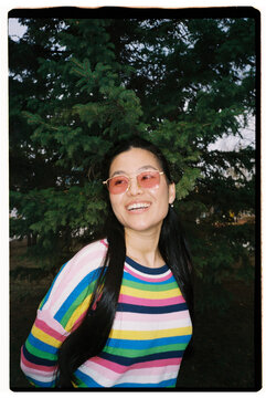 Smiling Woman in Colorful Sweater and Sunglasses Outdoors