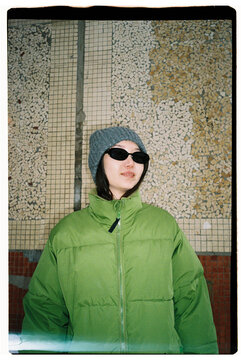 Portrait of Young Woman in Green Jacket Against Mosaic Wall
