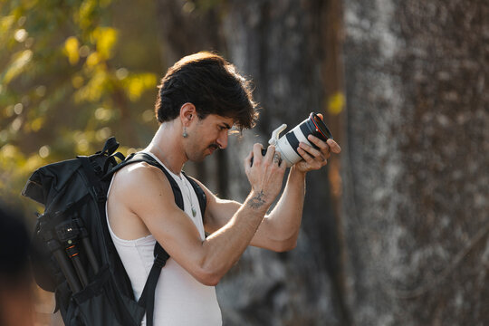 Man preparing telephoto lens on camera for outdoor photography