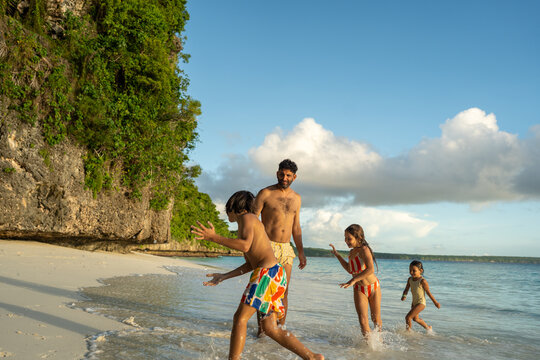 Father and children playing by the shoreline