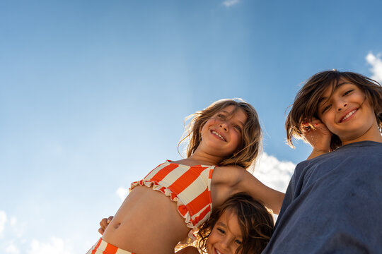 Children leaning together smiling down at camera, low angle. 