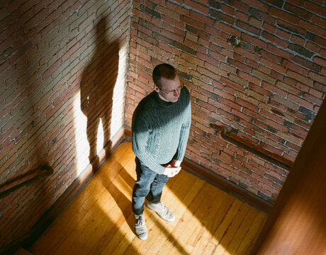 Indoor candid portrait of a man in a wooden and brick wall staircase.