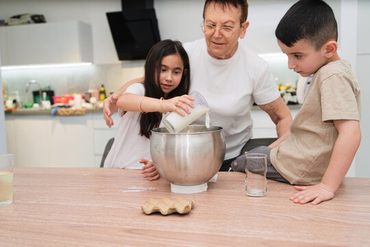 Grandmother Enjoys Baking Cake With Kids in a Home Kitchen