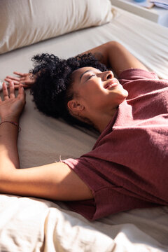 Woman basking in sunlight, relaxing on bed.