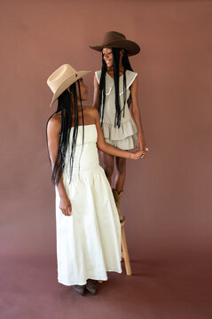 Two Women Stand Together in Hats During a Studio Portrait Session