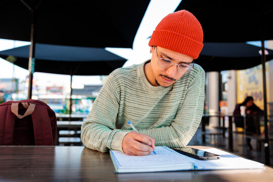 Student man taking notes at cafe