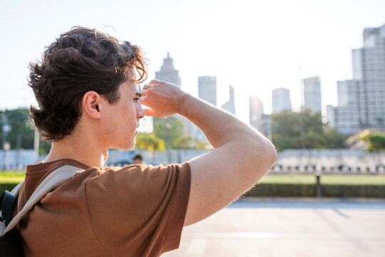 Man shields eyes, gazing at city skyline during urban heatwave