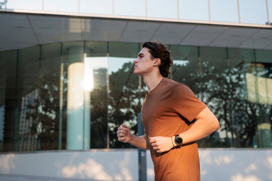 Man jogging in urban setting with fitness tracker