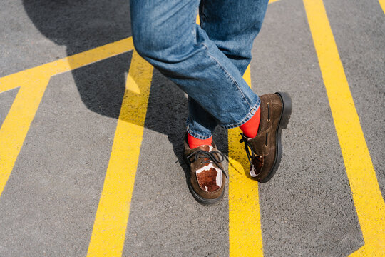 Brown shoes with red socks standing on bright yellow road