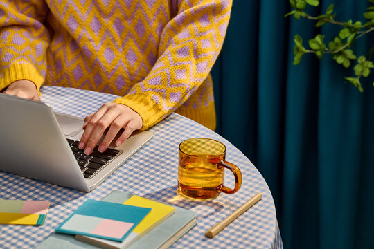 Person working on laptop at a table with a drink and notebooks