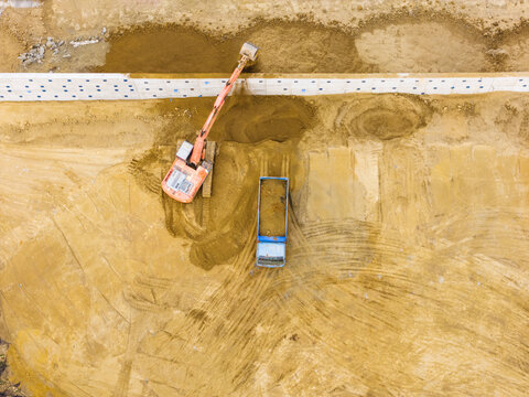 Excavator Backfilling Soil Along Construction Wall Aerial View