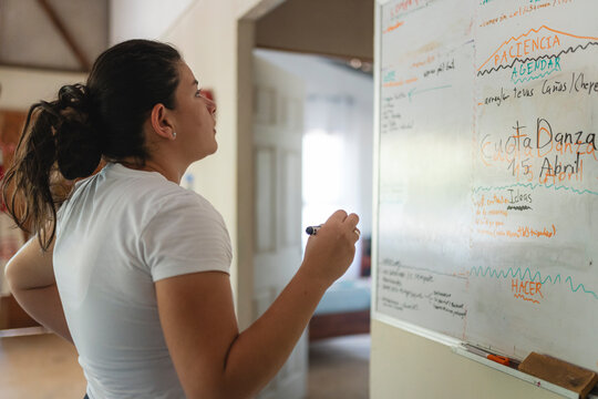 Woman writing notes on whiteboard planning future tasks